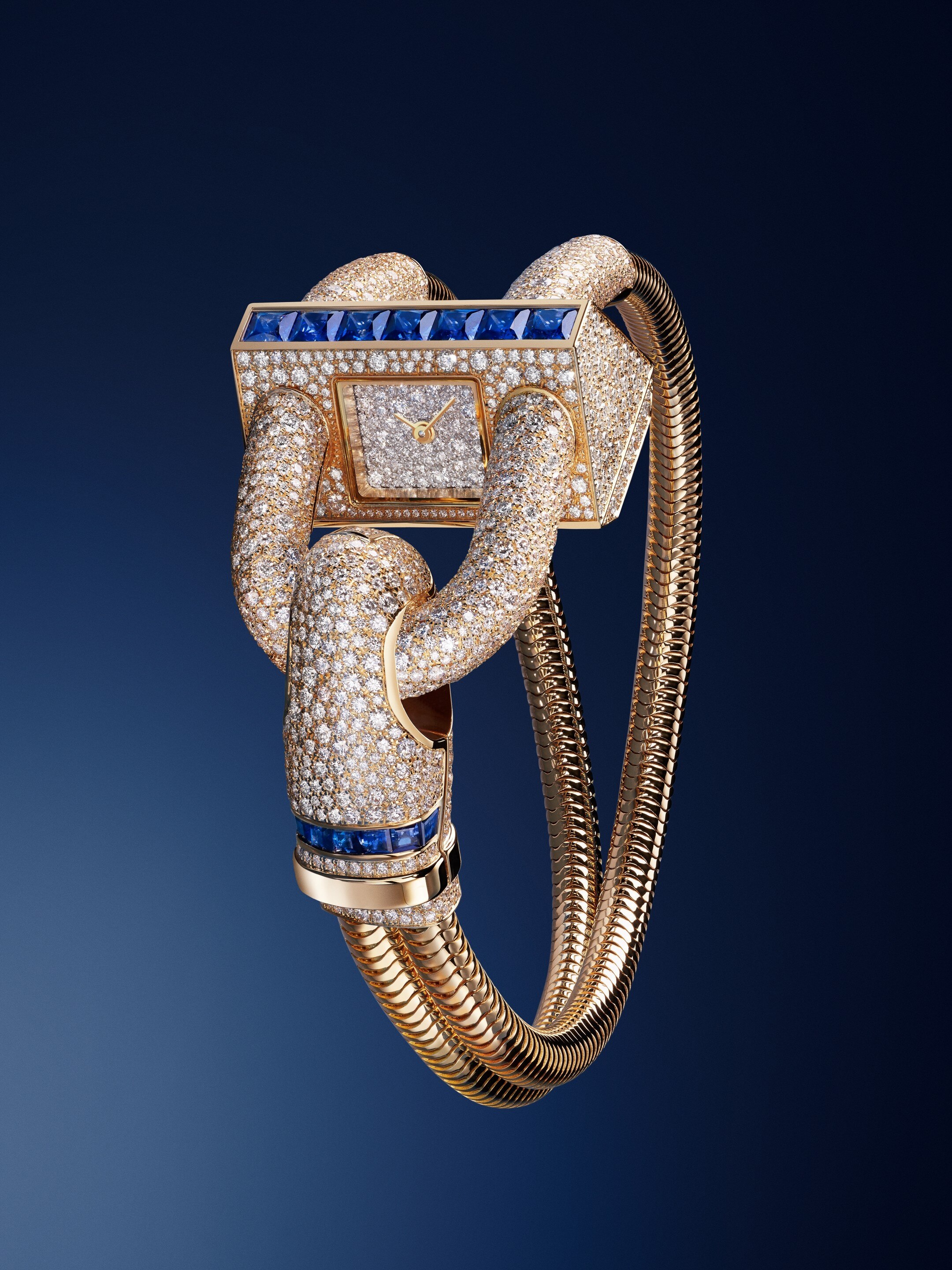 ساعة كادُنا. ذهب أصفر عيار 18 قيراط، سافير بقطع برنسيس، ماس مستدير مرصّع ترصيعًا ثلجيًا؛ طوق من الذهب الأصفر عيار 18 قيراط، وجه الساعة من الذهب الأبيض عيار 18 قيراط المطلي بالروديوم ، تاج من الذهب الأصفر عيار 18 قيراط، سوار بسلسلة بشكل الأفعى من الذهب الأصفر عيار 18 قيراط، مشبك من الذهب الأصفر عيار 18 قيراط، أحجار سافير بقطع مربع وشبه منحرف، حركة كوارتز سويسرية. مجموعة كادُنا. دار فان كليف أند آربلز.