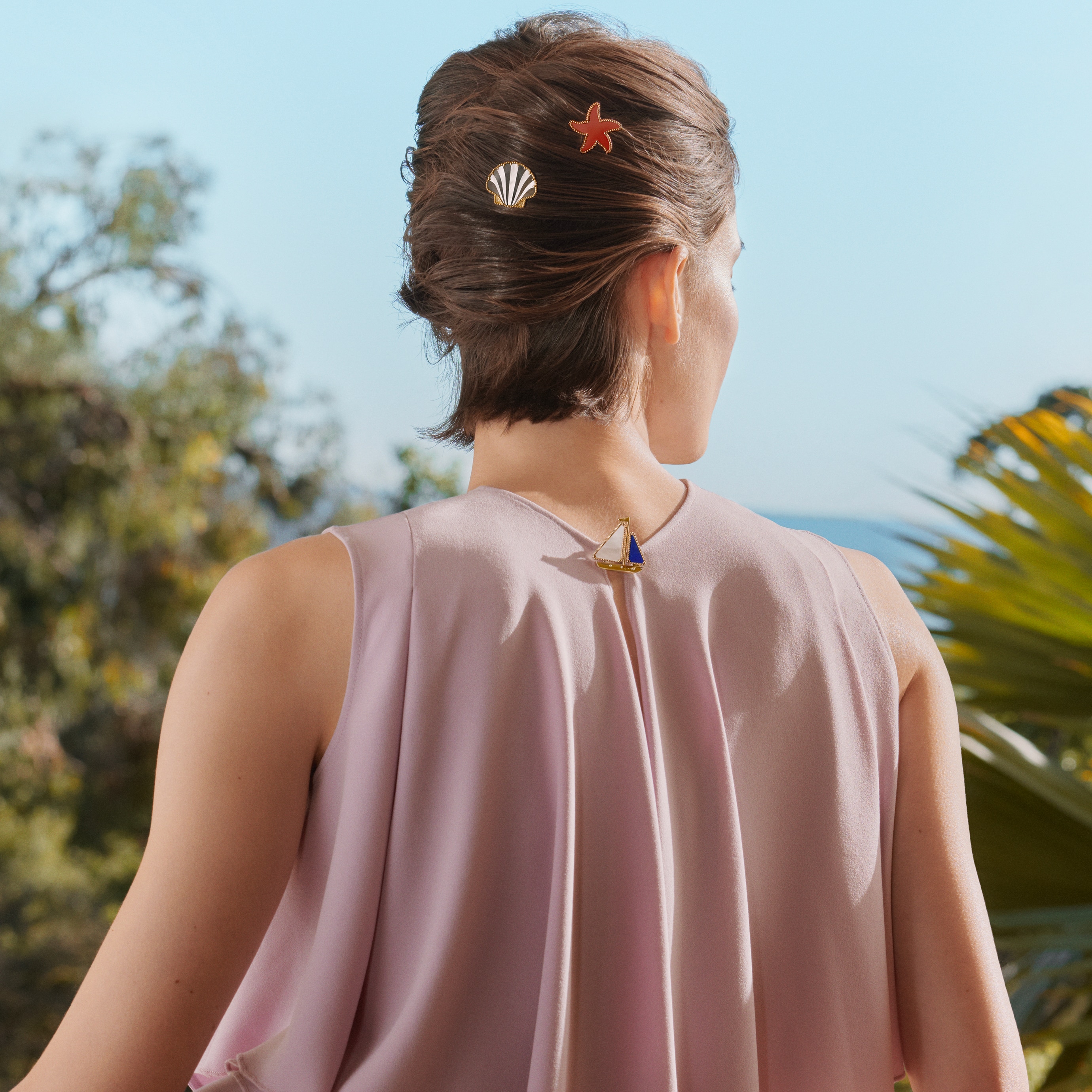 Clip Estrella de mar, oro rosa, jaspe rojo; clip Barco, oro amarillo, lapislázuli, nácar blanco; y clip Concha, oro amarillo, nácar blanco, nácar gris. Colección Lucky Summer, Van Cleef & Arpels.
