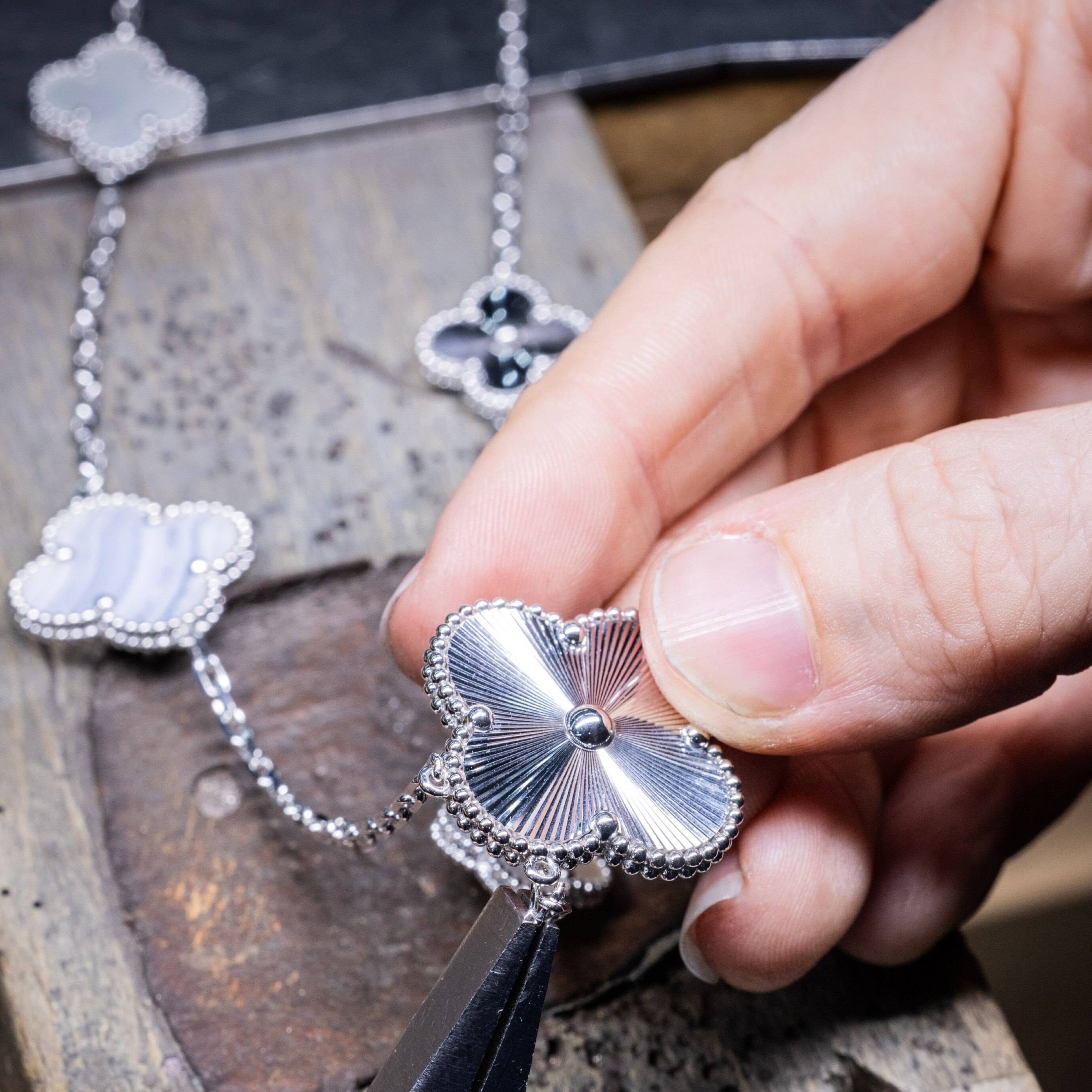 Assembling the motifs and the chain of the Magic Alhambra transformable long necklace, Van Cleef & Arpels.