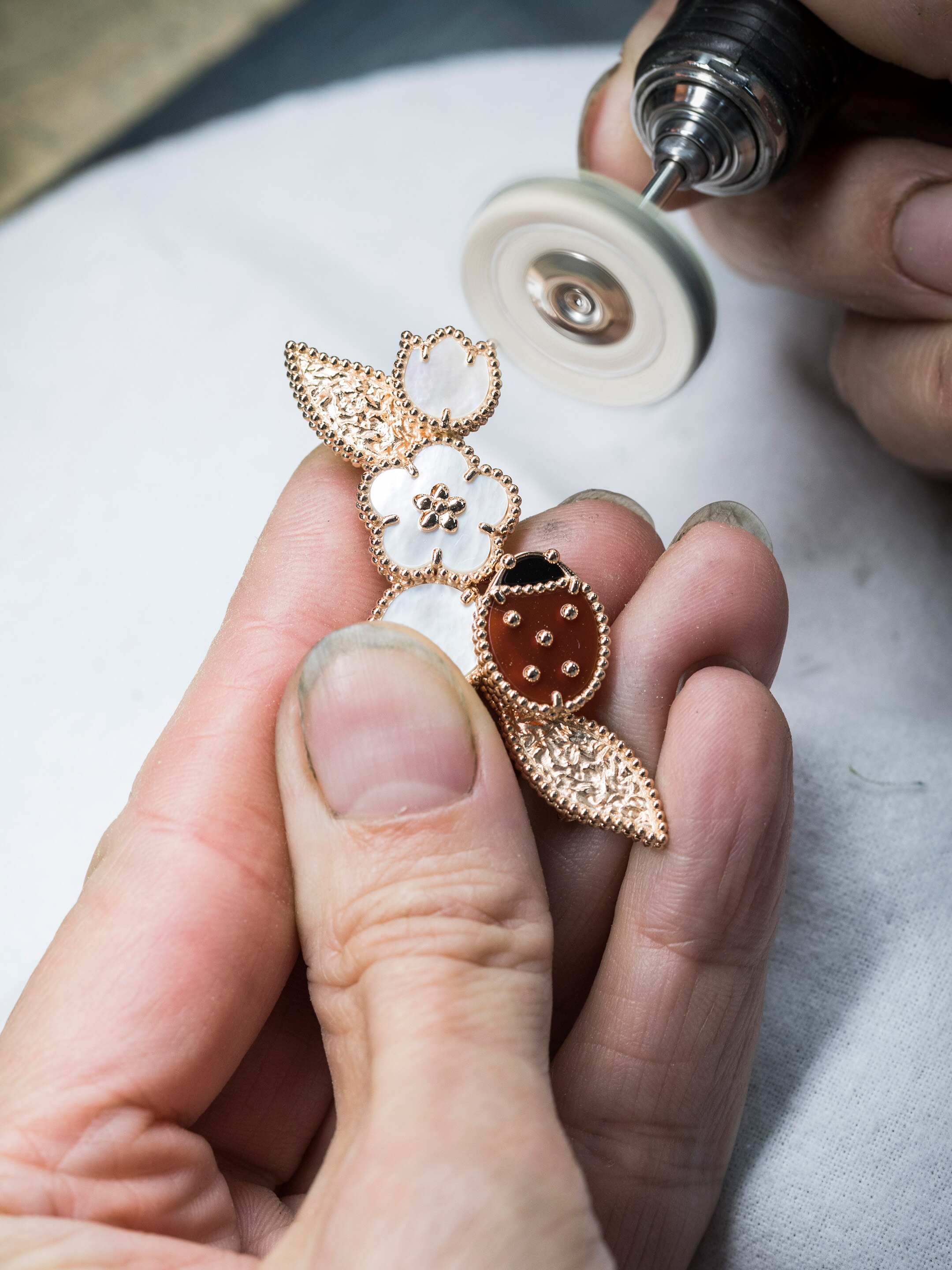 Final polishing work. Lucky Spring clip, 18K rose gold, white mother-of-pearl, carnelian, onyx. Lucky Spring collection, Van Cleef & Arpels.